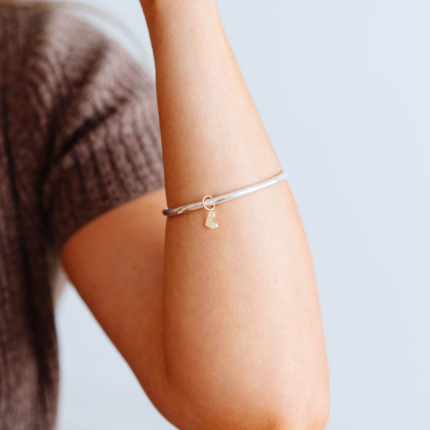 Thick silver bangle with gold dangling heart charm