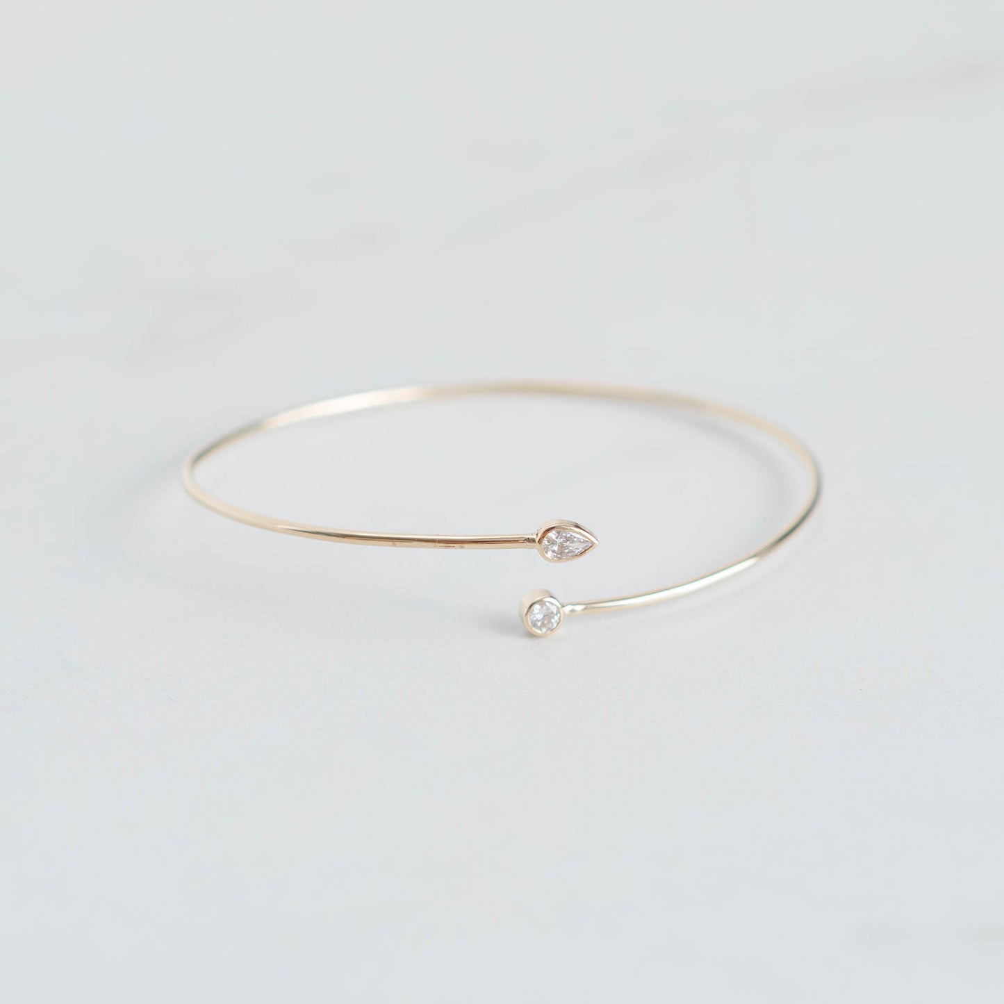 Gold bracelet with small heart and pearl charms on a light gray background