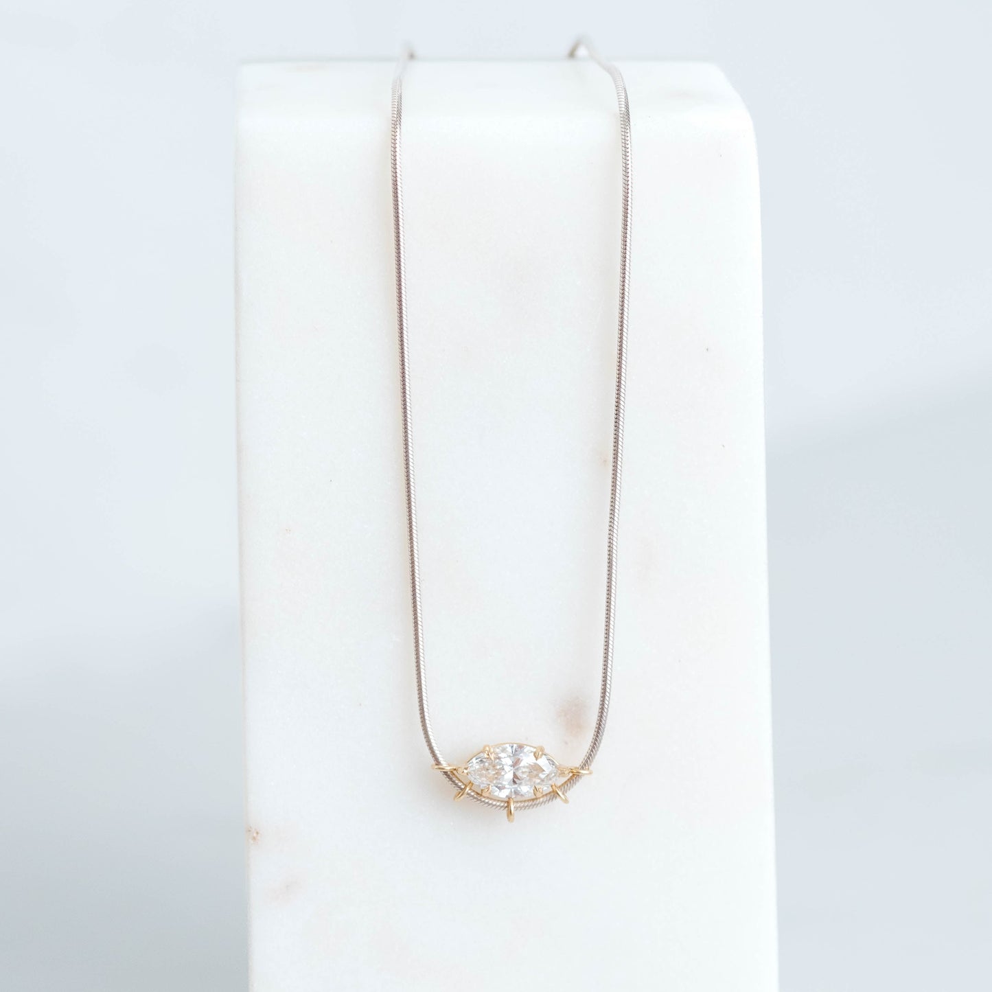 3ct marquise lab grown diamond set in a 6 claw yellow gold basket setting. Suspended on a silver snake chain.