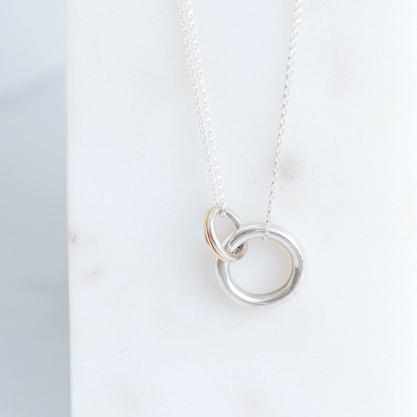 Silver necklace with interlocking rings on a white surface