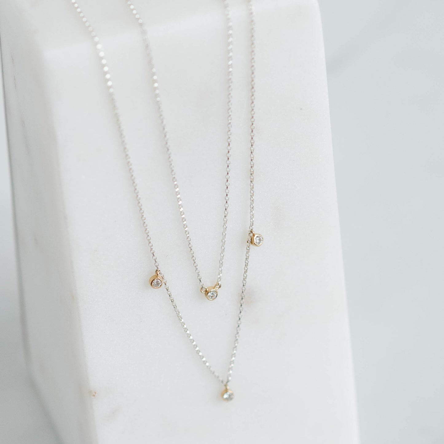 double silver rolo chain with four lab grown round brilliant set in yellow gold bezels.