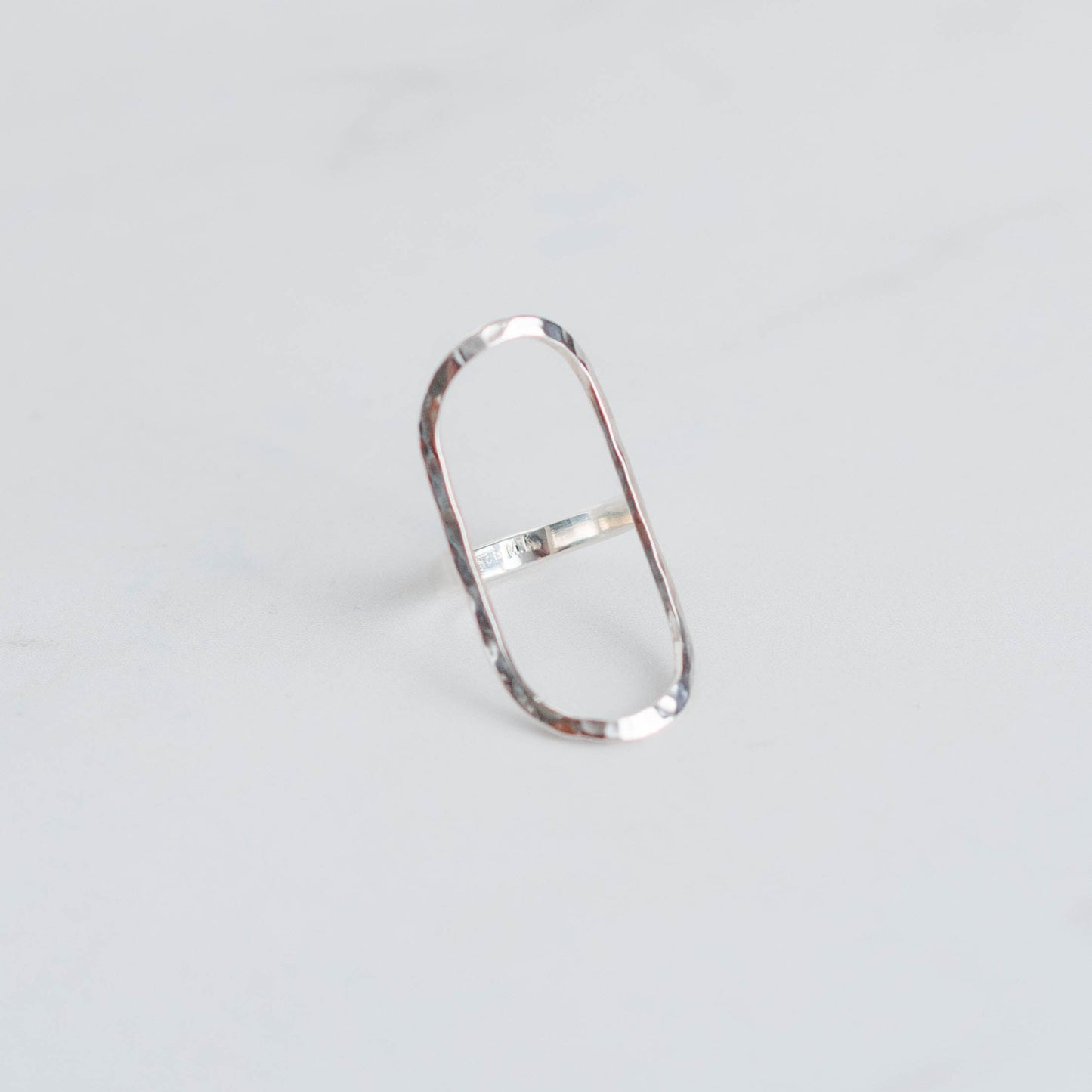 Silver ring with a large oval frame and a hammer finish.
