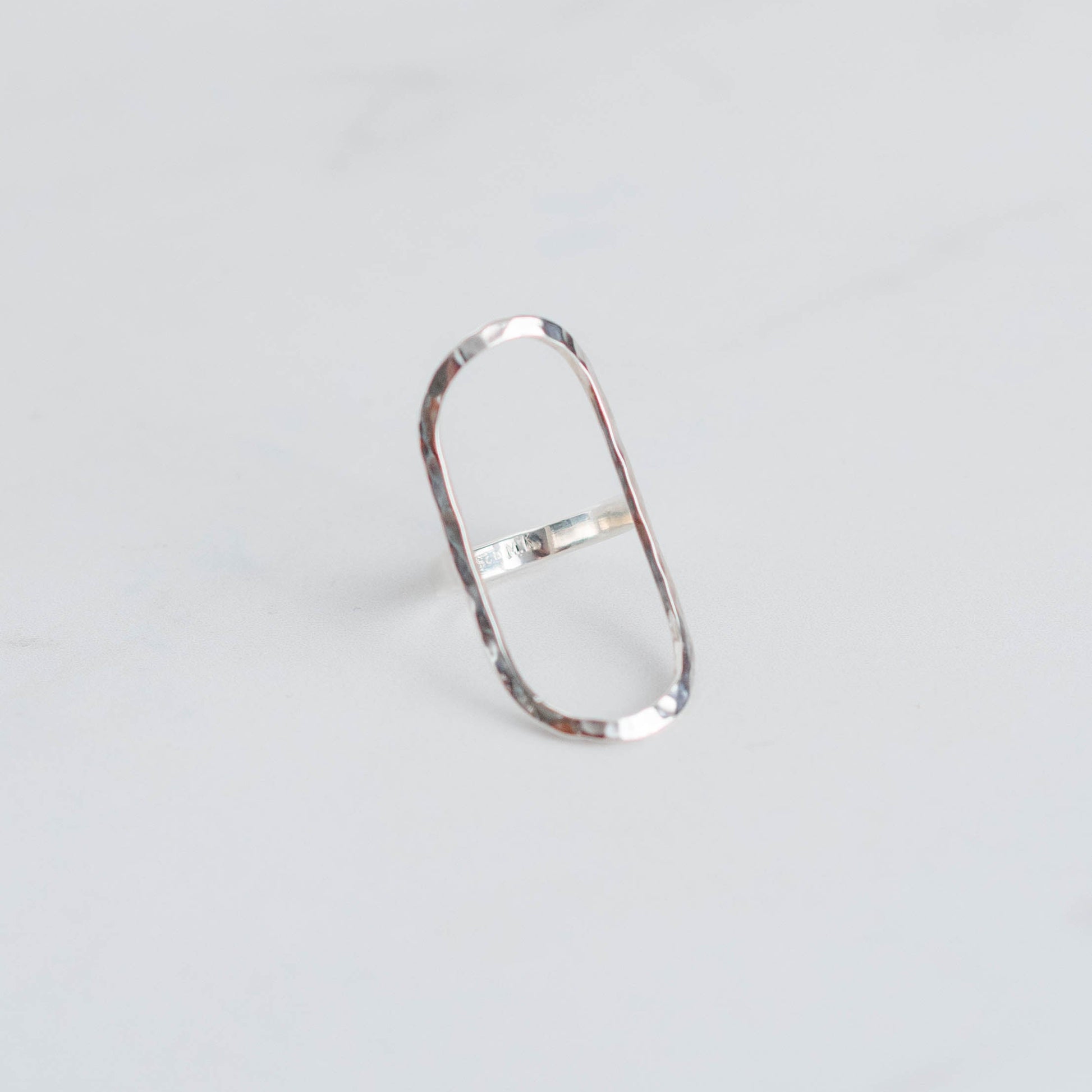 Silver ring with a large oval frame and a hammer finish.