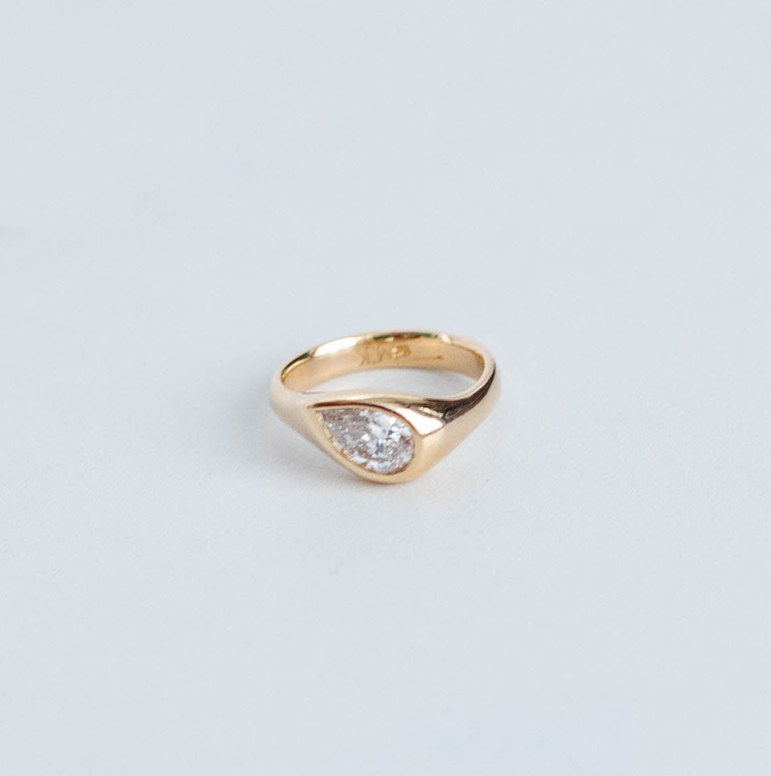Gold pinky ring with 0.80ct pear cut diamond bezel set in ring.