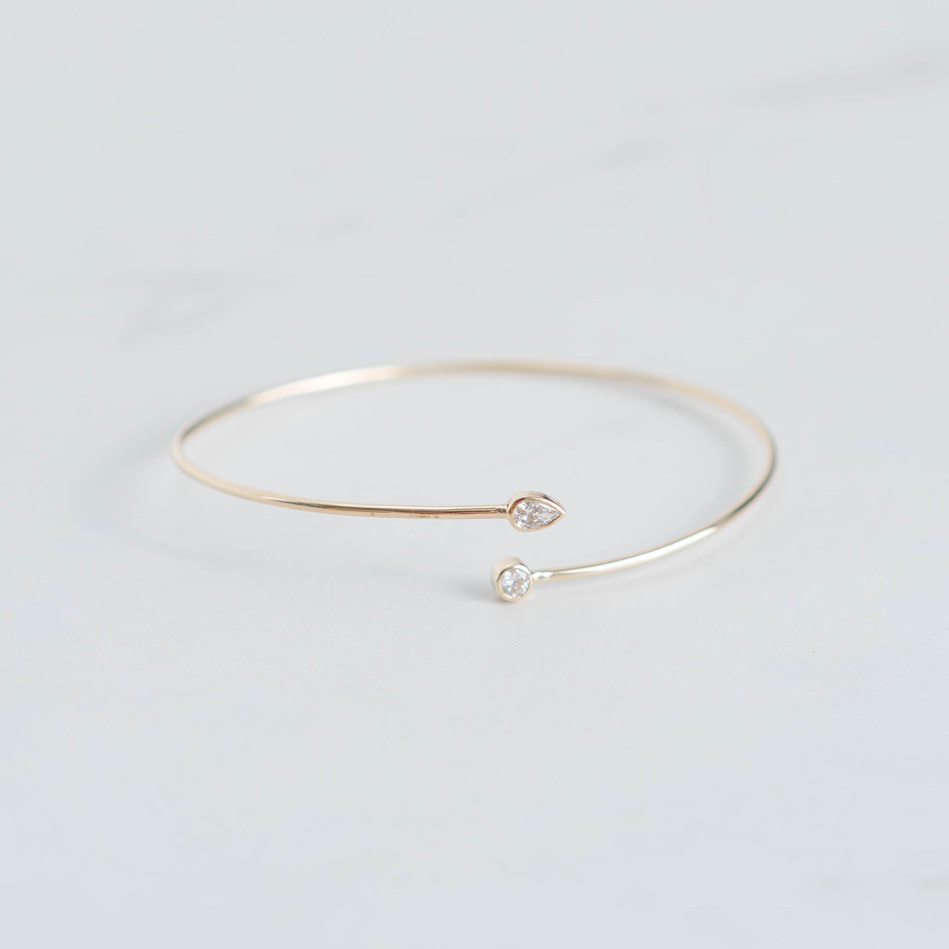 Gold bracelet with small heart and pearl charms on a light gray background