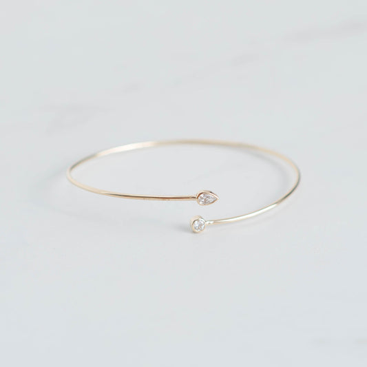 Gold bracelet with small heart and pearl charms on a light gray background