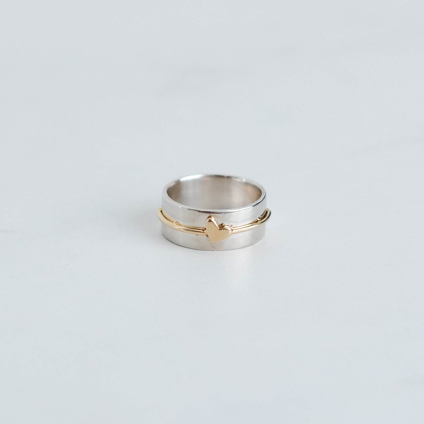 wider sterling silver band with yellow gold wire and a tiny heart.