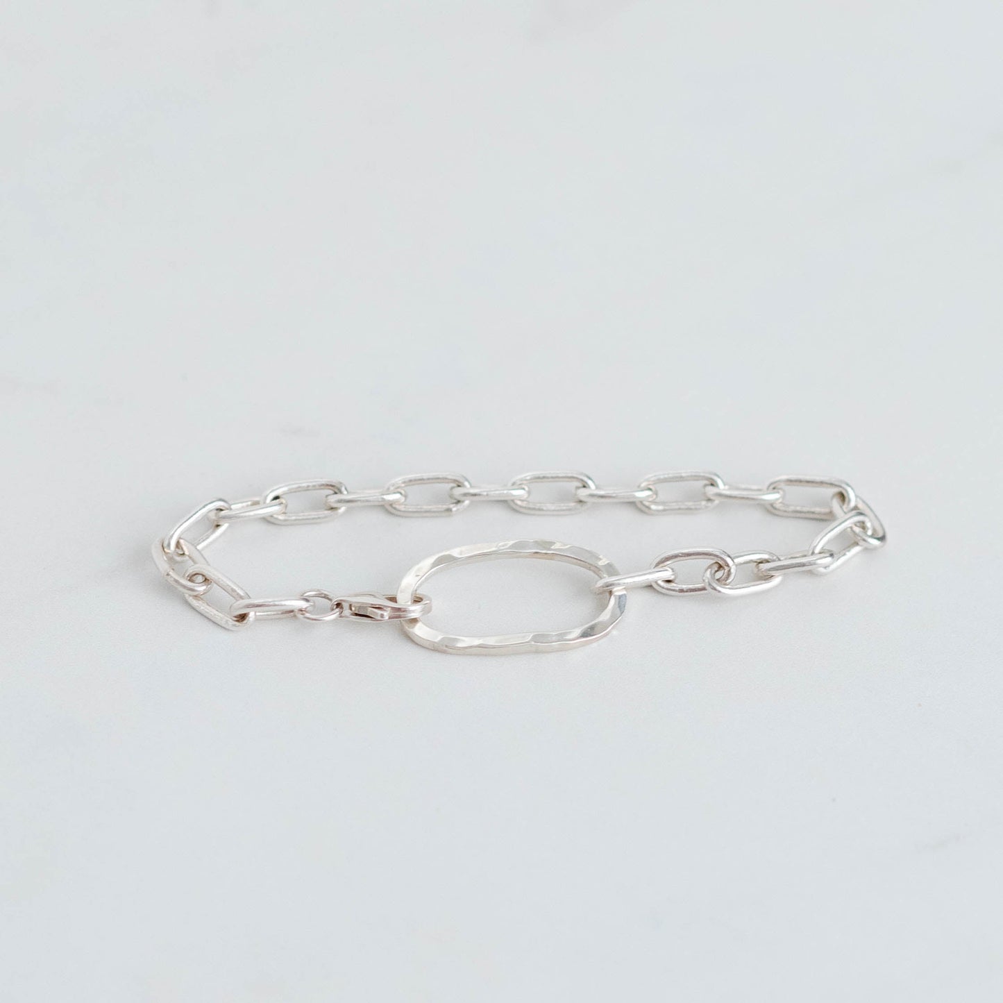 Handmade silver paperclip chain with an oval hammered centre piece. Linked together with a silver trigger clasp.