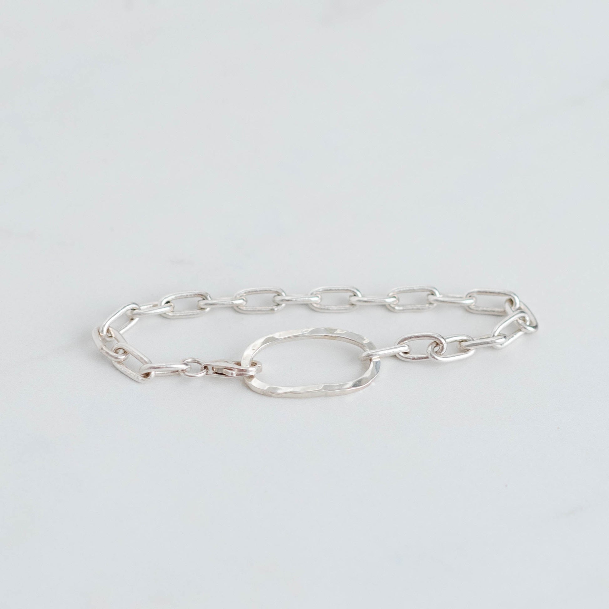 Handmade silver paperclip chain with an oval hammered centre piece. Linked together with a silver trigger clasp.