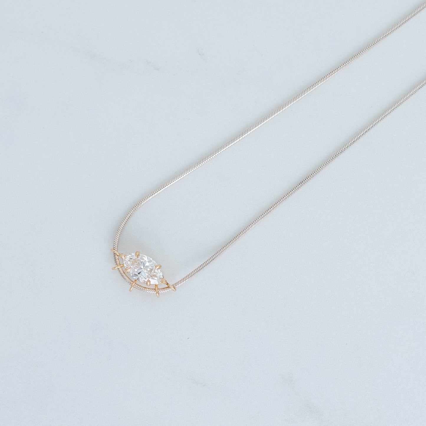 3ct lab grown marquis cut diamond set in a yellow gold basket setting, suspended on silver snake chain. 