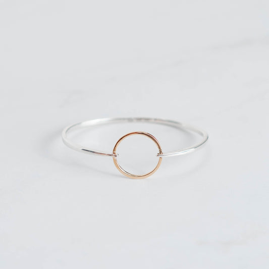 High polished silver bangle with a yellow gold ring connecting it. 