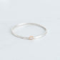 Silver bangle with a hammered finish and a 1ct lab grown emerald cut diamond set in 10K yellow gold bezel