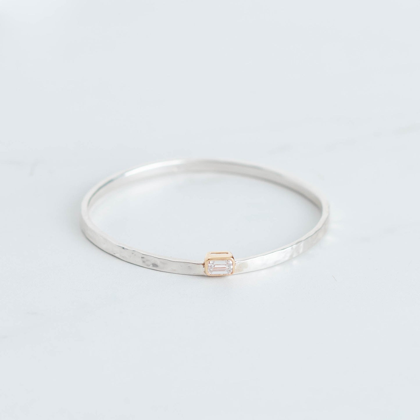 Silver bangle with a hammered finish and a 1ct lab grown emerald cut diamond set in 10K yellow gold bezel