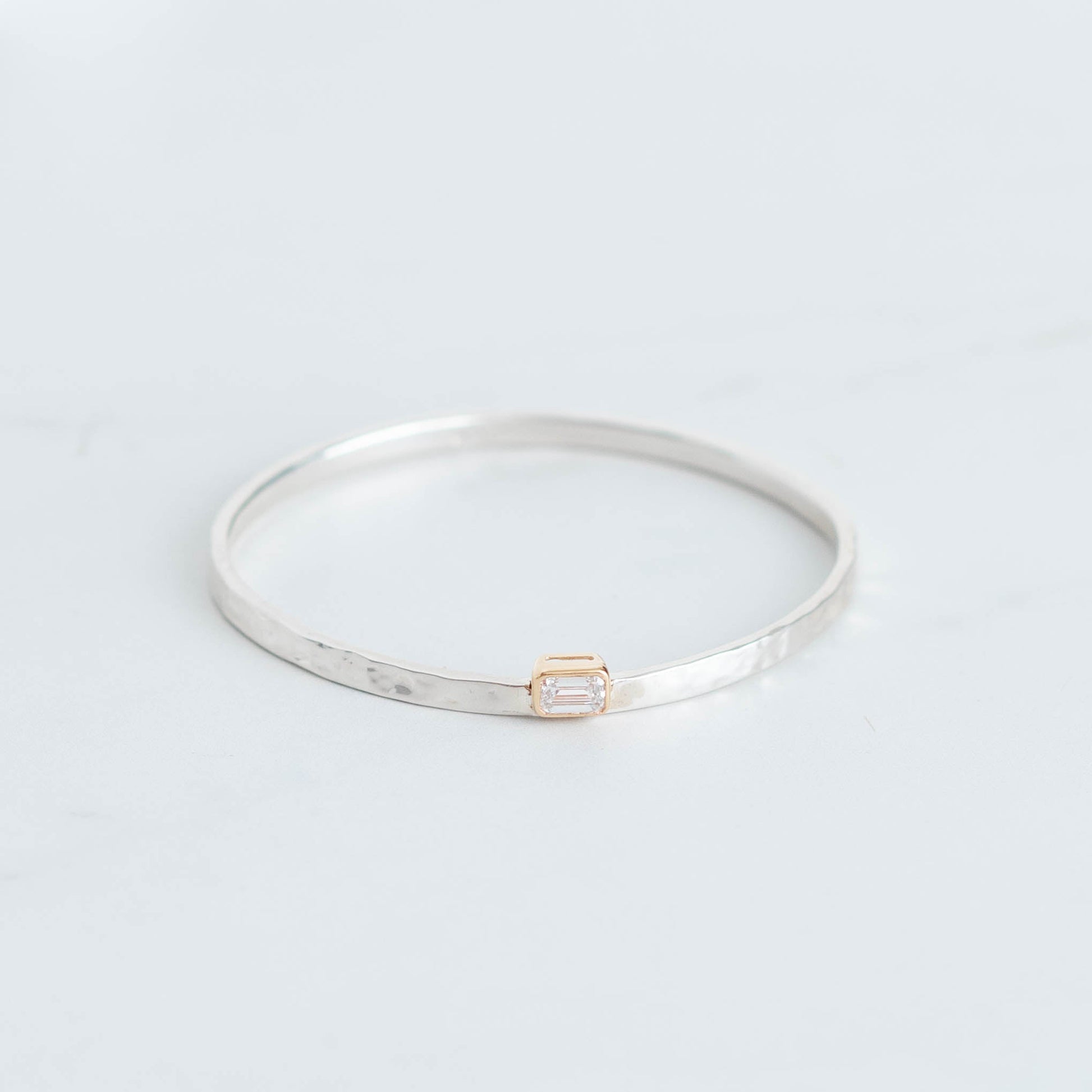 Silver bangle with a hammered finish and a 1ct lab grown emerald cut diamond set in 10K yellow gold bezel