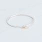 Sterling silver bangle with a connecting chain piece and a yellow gold toggle accent. 