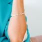 Sterling silver bangle with a connecting chain piece and a yellow gold toggle accent. 
