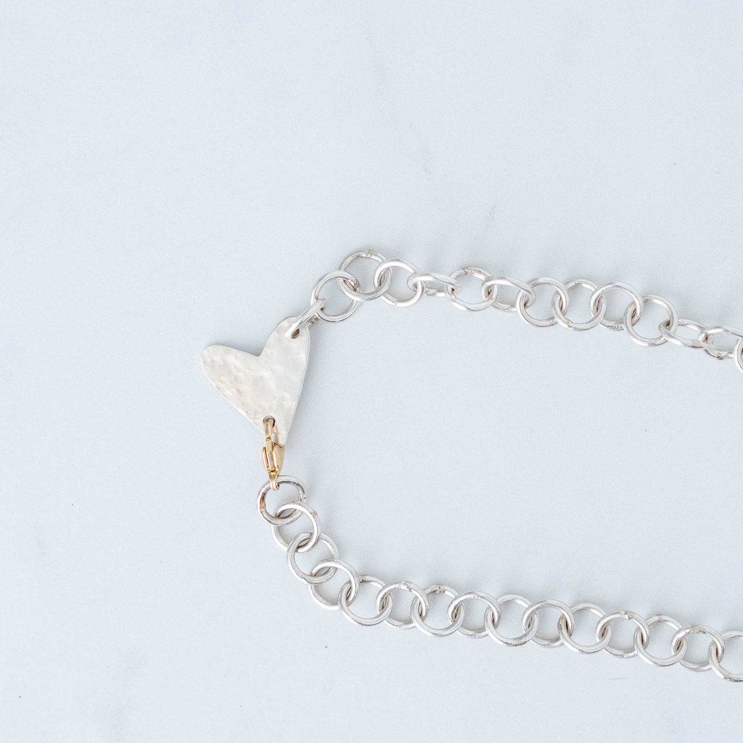 Handmade silver chain with hammered heart pendant with a 10K Yellow gold trigger clasp.