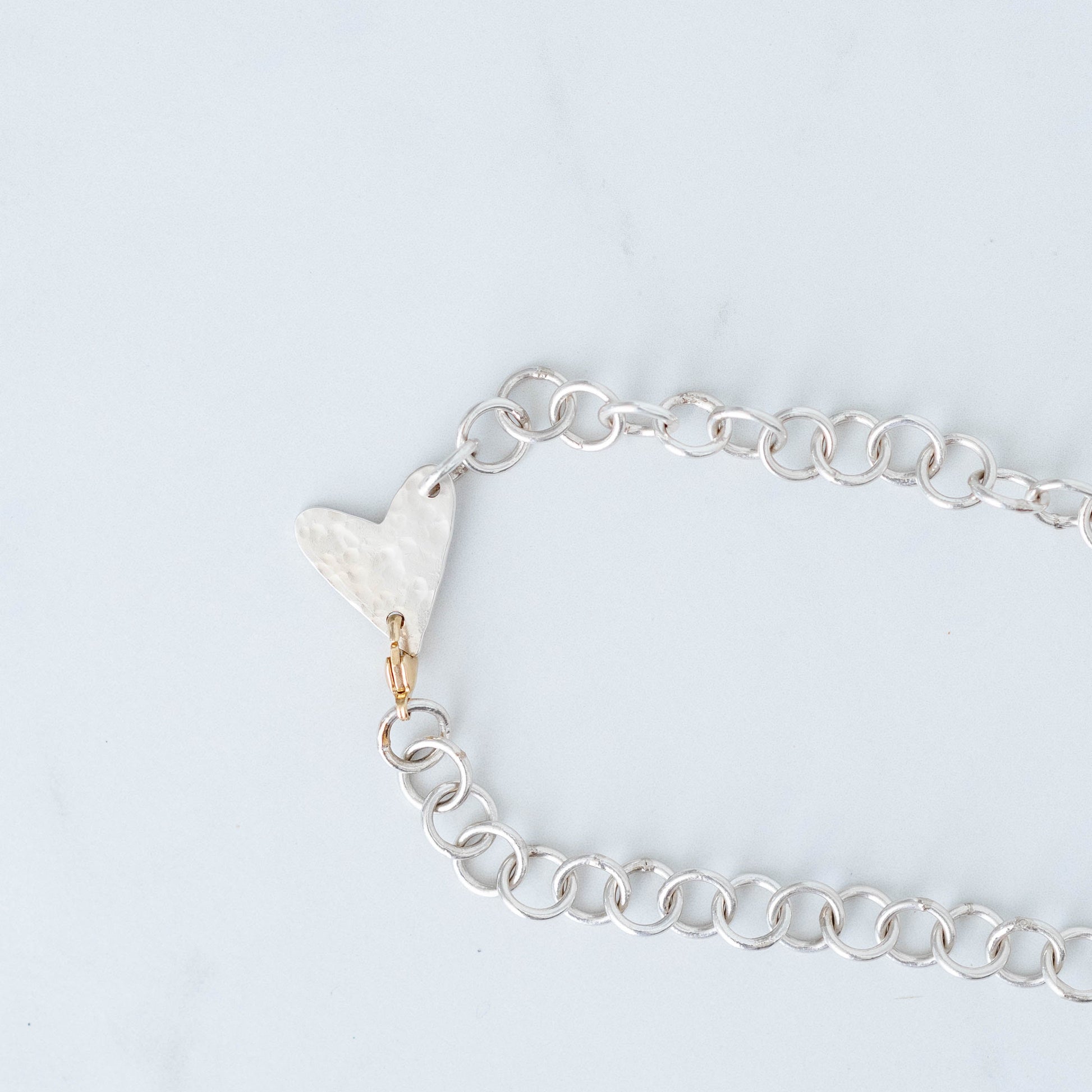Handmade silver chain with hammered heart pendant with a 10K Yellow gold trigger clasp.