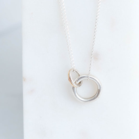 Silver necklace with interlocking rings on a white surface