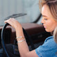 Woman driving a car with a focus on her hand on the steering wheel.