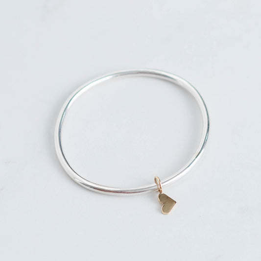 Thick silver bangle with gold dangling heart charm 